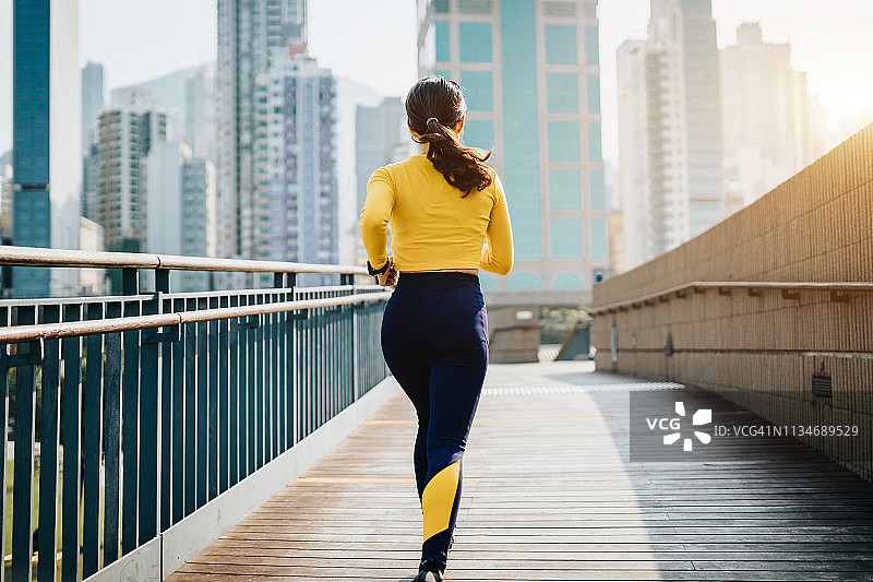 后视图自信年轻的亚洲女运动员在城市公园慢跑的城市图片素材