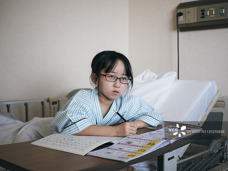 住院的日本女学生在床上做作业图片素材