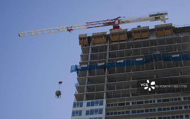 一幢摩天大楼的建筑工地正在用起重机吊起水泥图片素材
