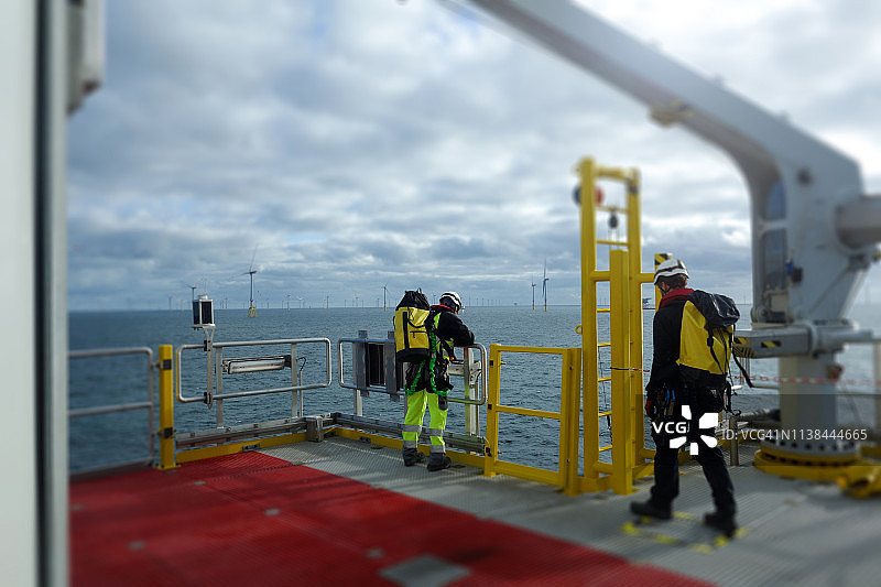 海上体力工人站在甲板上身后是风力涡轮机图片素材