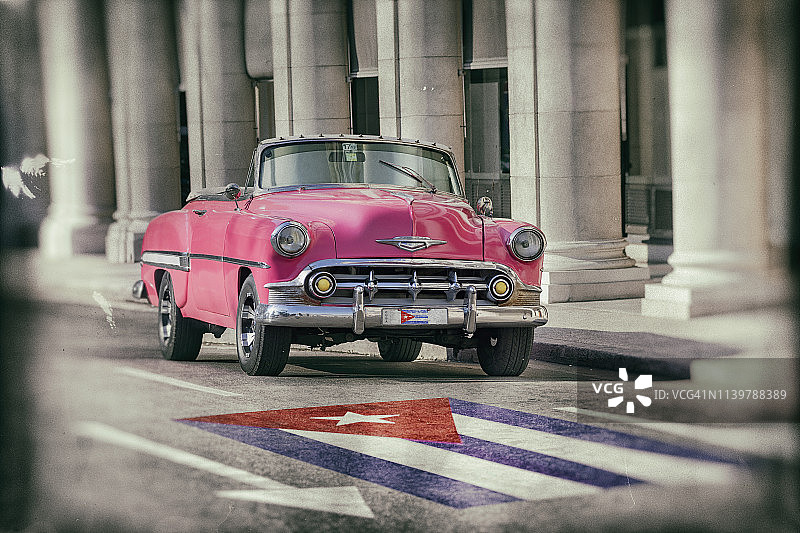 一辆粉红色老爷车穿过古巴哈瓦那老城图片素材