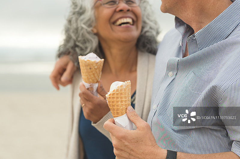 一对老年夫妇在海滩上一起享用甜筒冰淇淋图片素材