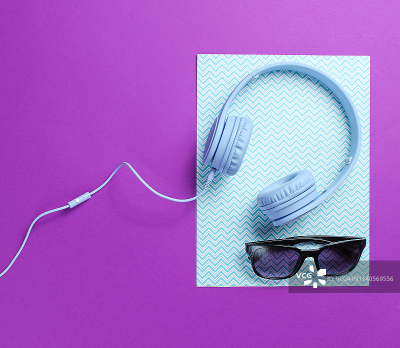 蓝色耳机有线，太阳镜上的蓝色紫色创意背景。极简主义。俯视图图片素材