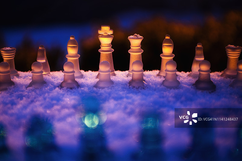 在一个下雪的冬天晚上在户外设置的象棋游戏。图片素材