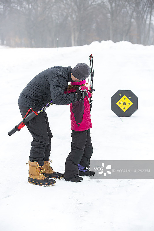 父亲和女儿在冬天户外练习射箭图片素材