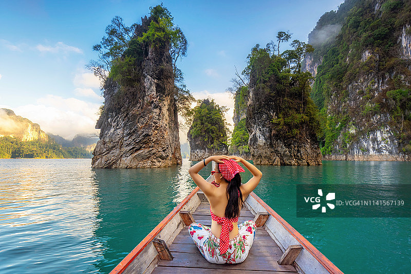 快乐的女人旅行者在船上她的双臂张开感觉自由，Ratchaprapa大坝在KHAO SOK国家公园，泰国，苏拉他尼，泰国旅游，美丽的目的地亚洲，夏季假期户外度假旅行图片素材