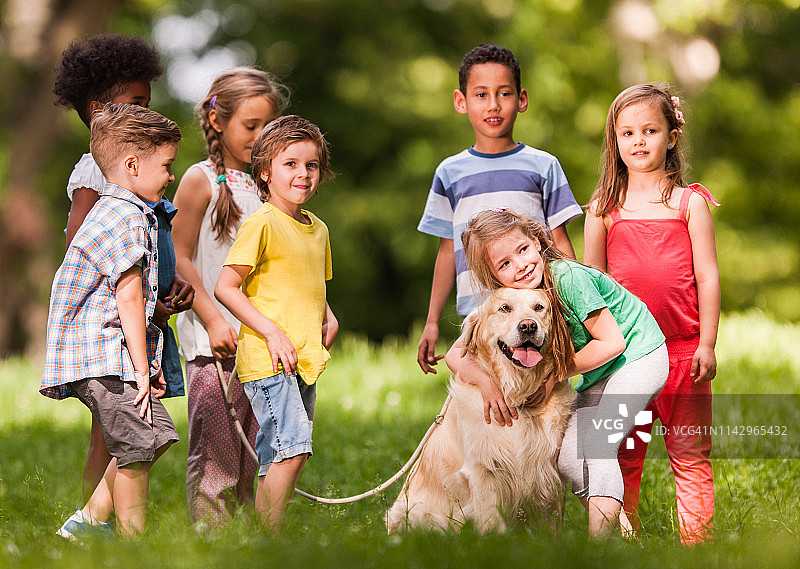 春天的一天，可爱的孩子们和金毛猎犬在公园里嬉戏。图片素材