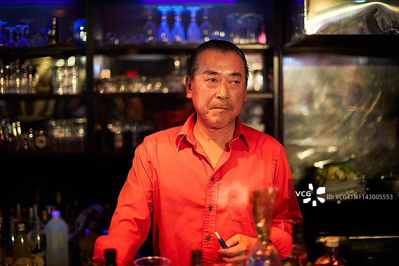 成熟的男酒吧老板站在吧台前图片素材