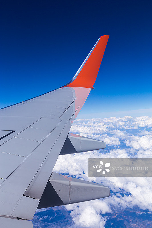鸟瞰图的云，蓝天和飞机机翼视图通过飞机窗口。图片素材