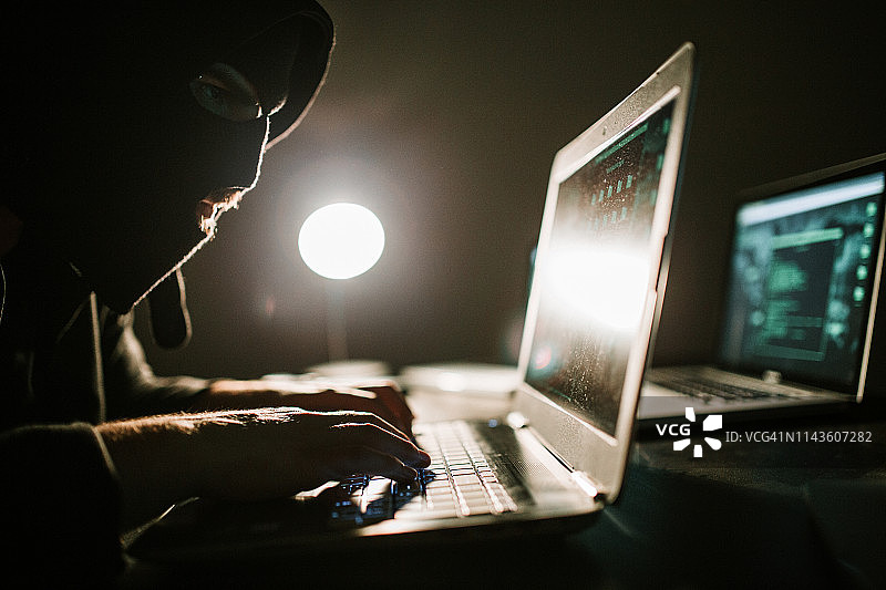 男子使用笔记本电脑进行黑客攻击和网络犯罪图片素材