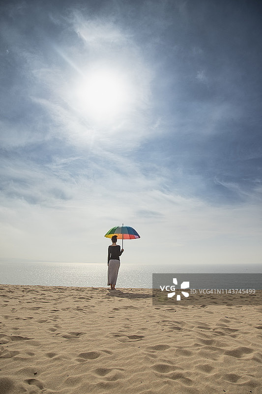 女人拿着五颜六色的雨伞站在沙滩上，后视镜图片素材