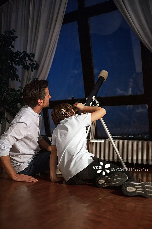 可爱的男孩和他的父亲通过望远镜看天空图片素材