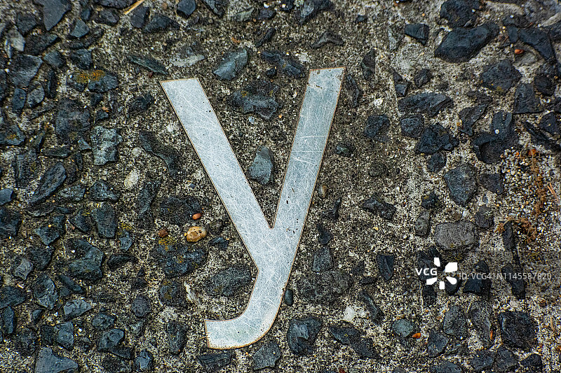 嵌在公路上的金属字母中的一个小字母图片素材