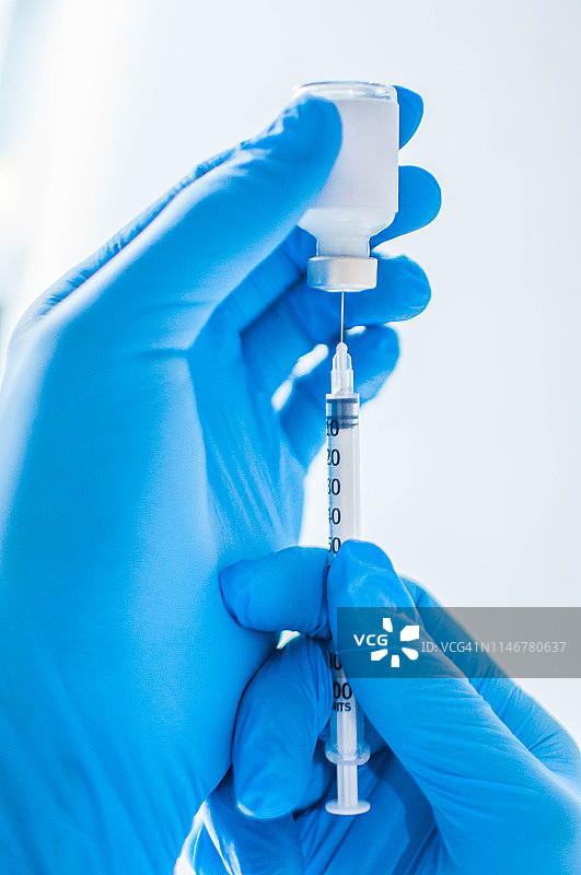 一个年轻的医生拿着一个药瓶和一个注射器图片素材