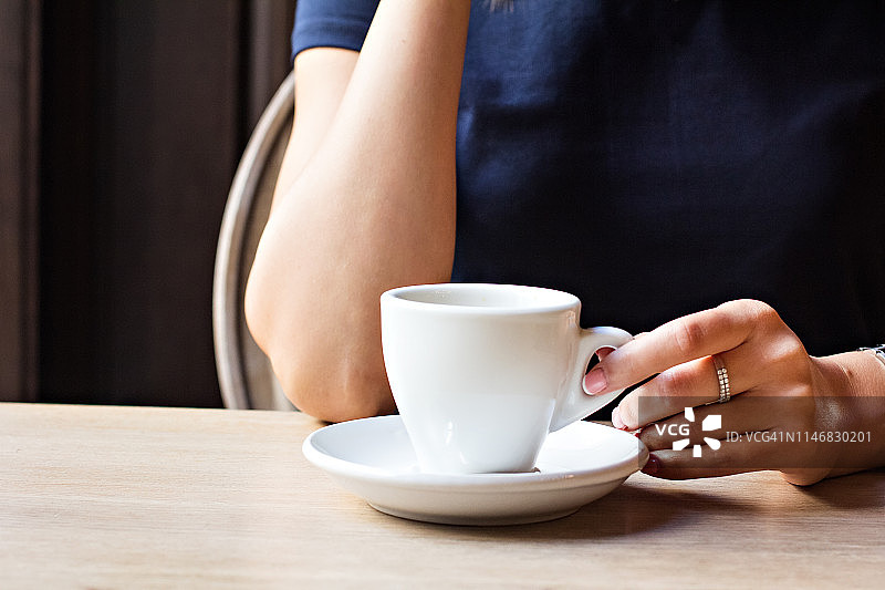 咖啡馆里的一杯咖啡和一个女孩的手。图片素材