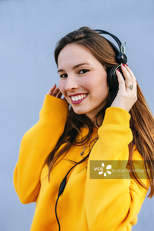 微笑的年轻女子戴着耳机听音乐的肖像图片素材