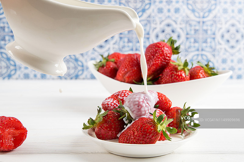 近,宏。法国的普罗旺斯。有人把牛奶(奶油)倒进一盘美味的红草莓里。图片素材