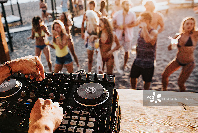 一个DJ在海滩派对上播放音乐的特写。图片素材