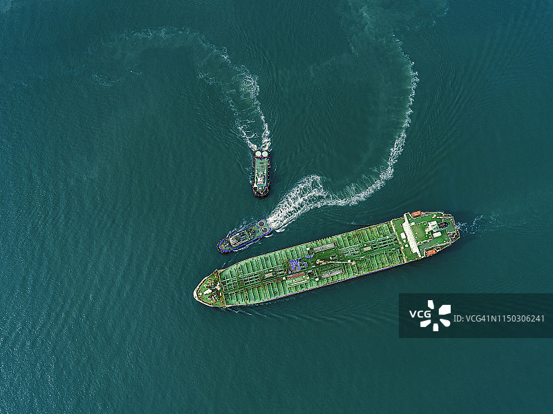 高空鸟瞰图拖船拖油船在绿色海洋的油轮去炼油厂装卸油运输。图片素材