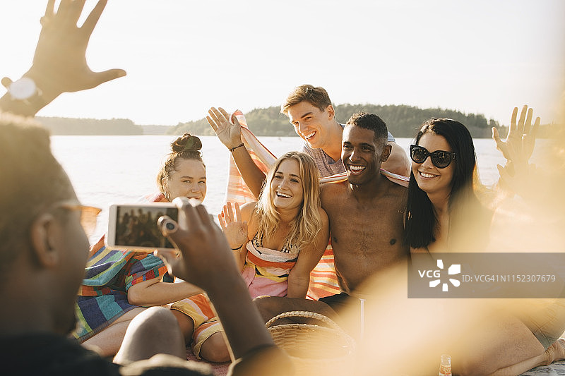 夏天，一名男子在码头用智能手机拍摄快乐的朋友图片素材