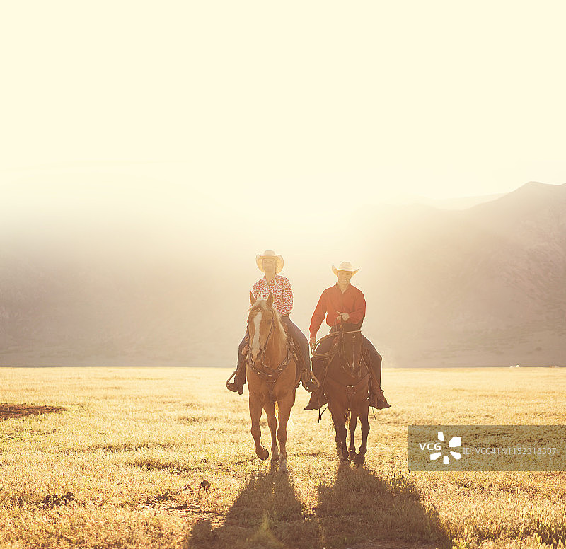 牧场主夫妇在日出时分骑马图片素材