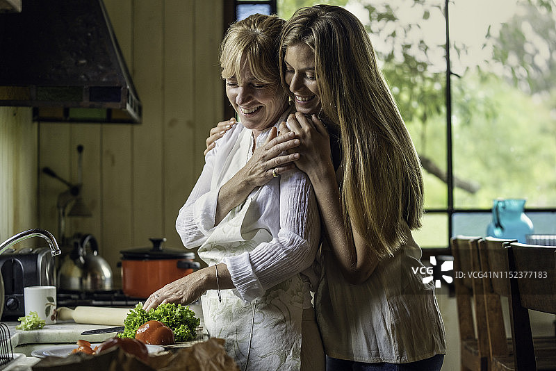女儿在厨房拥抱母亲图片素材