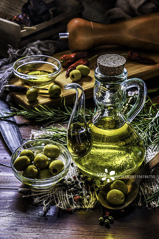 装橄榄的橄榄油瓶子。安排在老式乡村厨房的桌子上。图片素材