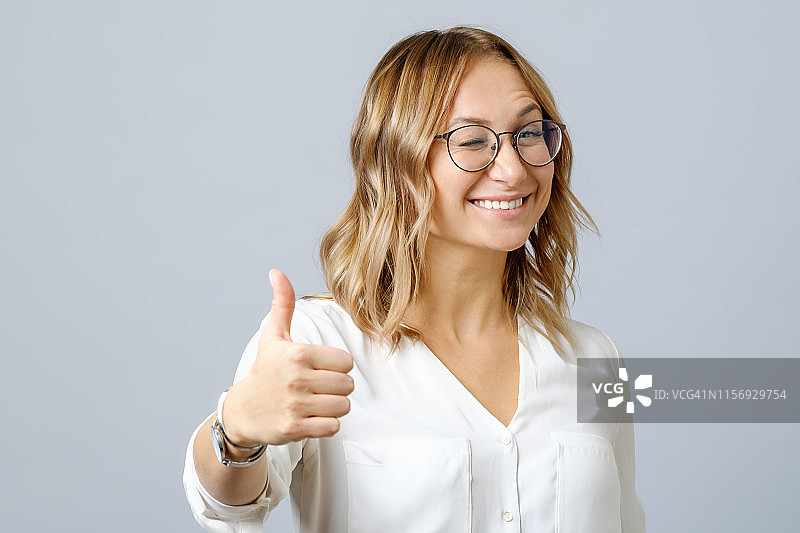 年轻快乐的微笑快乐的女人显示大拇指向上的手势孤立在灰色图片素材