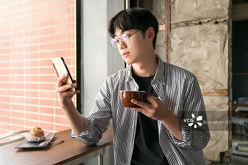 年轻人在现代咖啡馆里浏览智能手机。图片素材