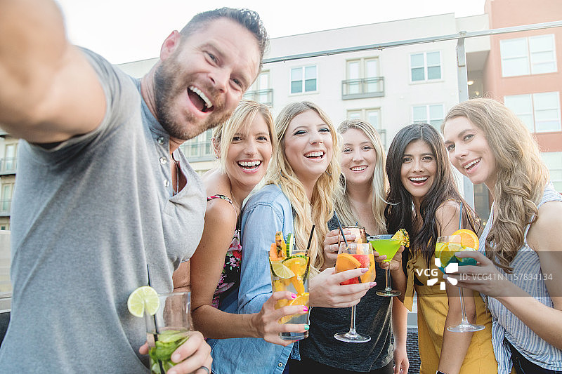 一群朋友一起在屋顶酒吧玩的时候自拍，喝鸡尾酒图片素材