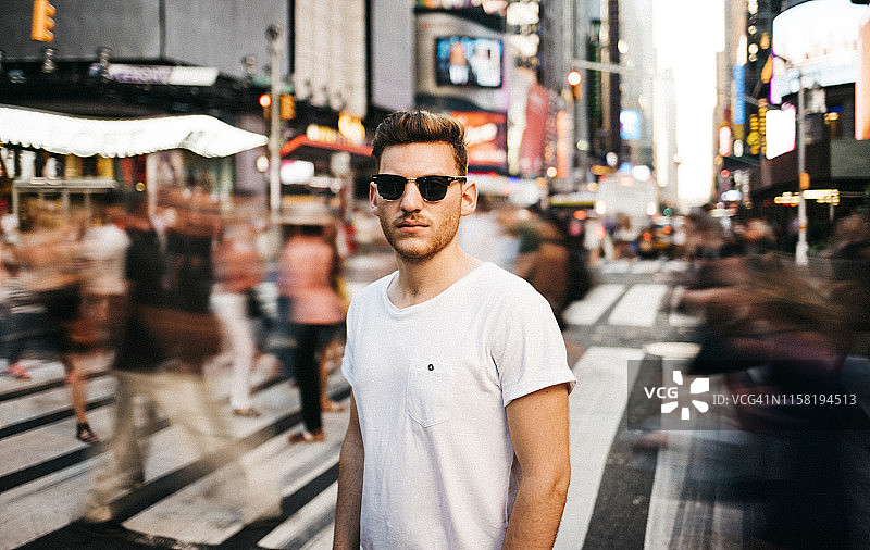 一名游客戴着太阳镜在纽约繁华的城市街道上的肖像图片素材