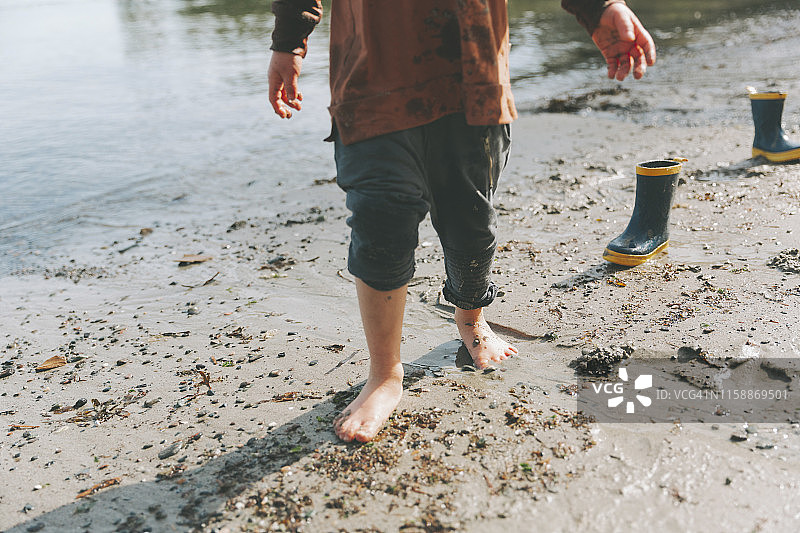男孩在沙滩上玩耍，赤脚在泥里走图片素材