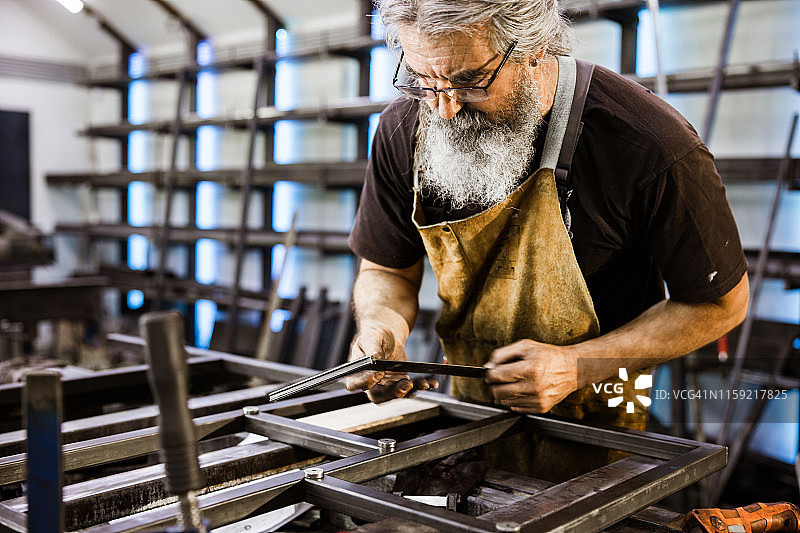 成熟的钢铁工人在钢铁车间工作时使用计量器具。图片素材