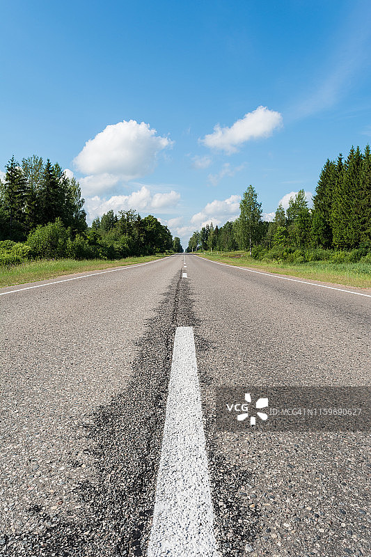 现代沥青路面带有道路标记元素。透视视图的双车道高速公路通过森林图片素材
