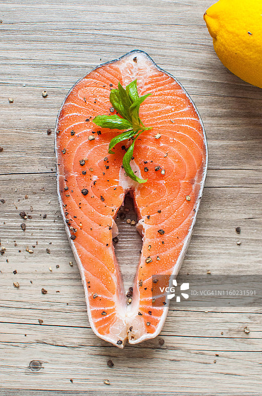 新鲜调味的生鲑鱼排和柠檬在木桌上图片素材