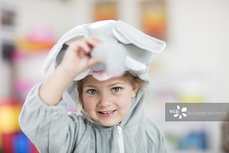 在幼儿园里穿着大象服装的快乐女孩的肖像图片素材