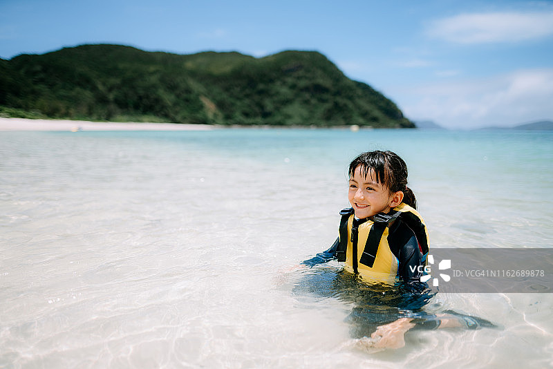 穿着救生衣的学龄前女孩在日本冲绳热带水域的肖像图片素材