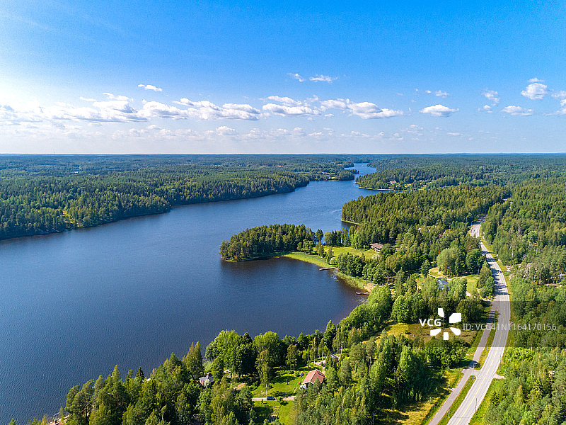 鸟瞰图蓝色的湖泊，道路和绿色的森林在一个阳光明媚的夏天在芬兰图片素材