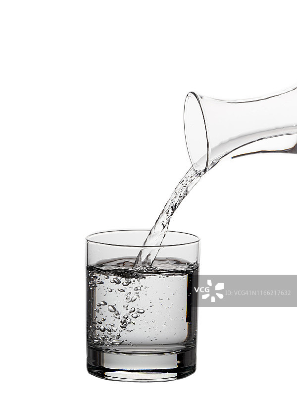 白色背景上的玻璃瓶水装满了一个饮用玻璃杯。图片素材