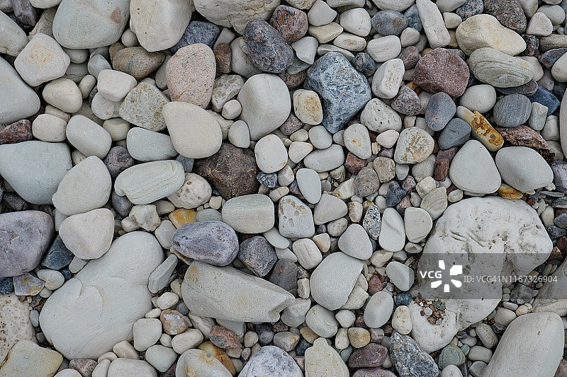 夏天白天，海边沙滩上有大小不一、形状各异的圆形石头图片素材
