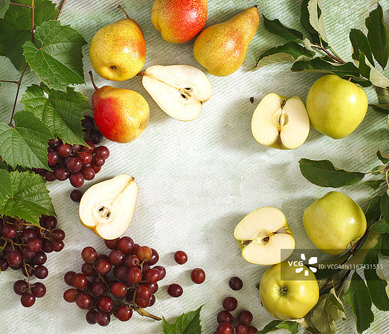 有机水果在浅绿色的背景。新鲜的葡萄、梨和带叶子的苹果图片素材