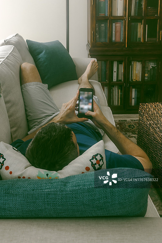 沙发上的男人休息室和智能手机图片素材