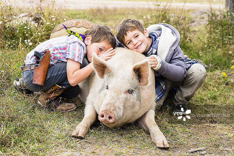 中美洲，墨西哥，杜兰戈，约翰韦恩农场，拉霍亚农场，两个孩子抱着一头猪图片素材