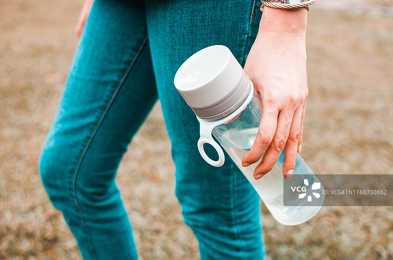 一名年轻女子在户外拿着一个可重复使用的水瓶容器图片素材