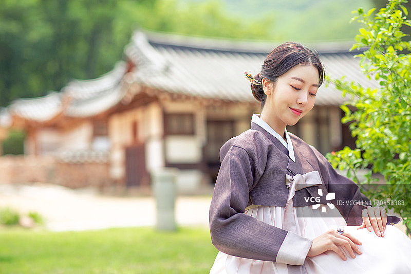 身着韩服的女子站在韩国传统民居前图片素材