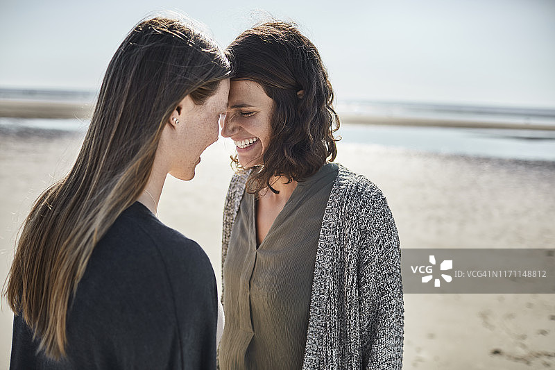 两个快乐的年轻女人在海滩上头对头图片素材