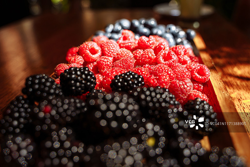 新鲜的有机浆果-黑莓，覆盆子，蓝莓放在木板上图片素材