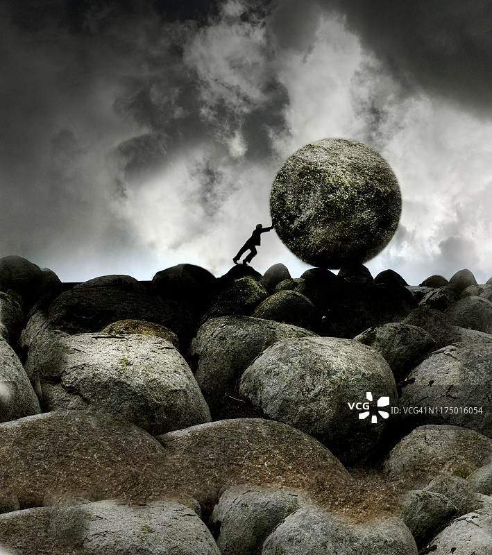 一个人推着一块巨石越过描绘逆境的岩石，图片素材