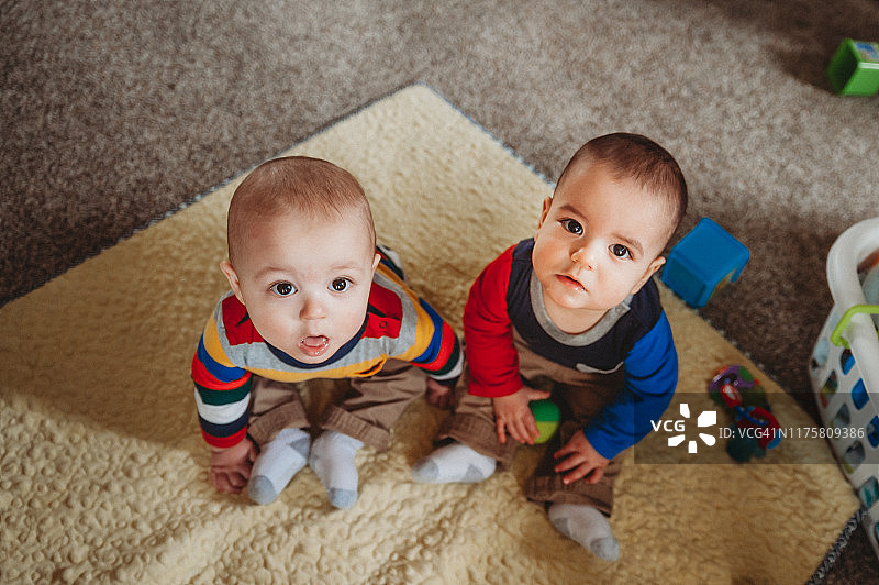 胖乎乎的8个月大的双胞胎男孩在生活中玩耍，都看着摄像机图片素材