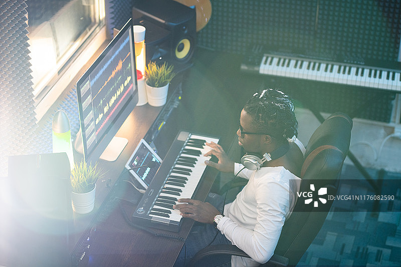 年轻的非洲音乐家穿着休闲装看着电脑屏幕的工作场所图片素材